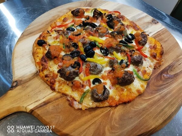 A pizza served on a wooden board from the dining menu at Awatuna Sunset Lodge