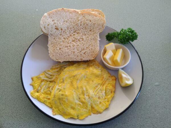 Two whitebait patties served with bread, butter, lemon and parsley.